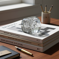 Hand-blown glass paperweight with trapped bubbles on stack of design monographs